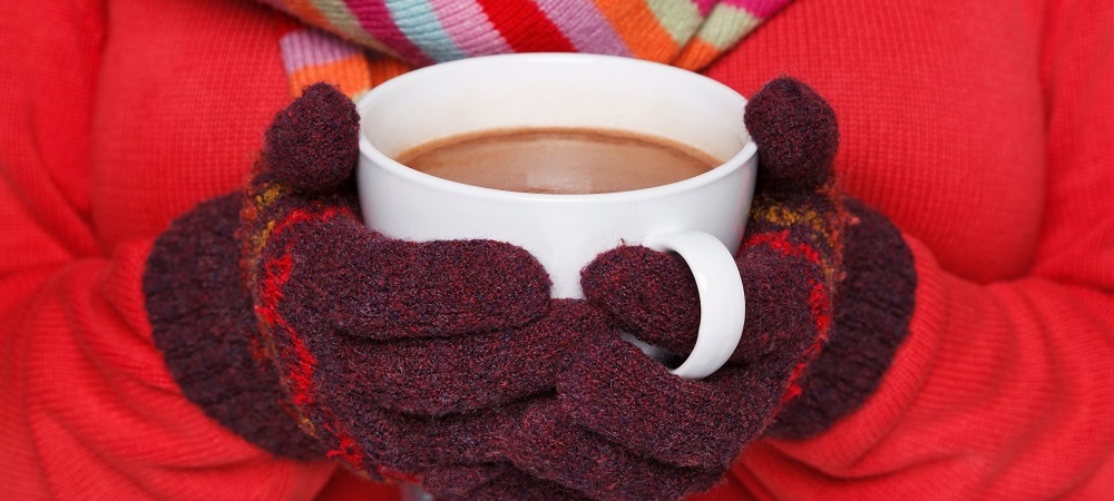 Hands in gloves holding a cup of coffee