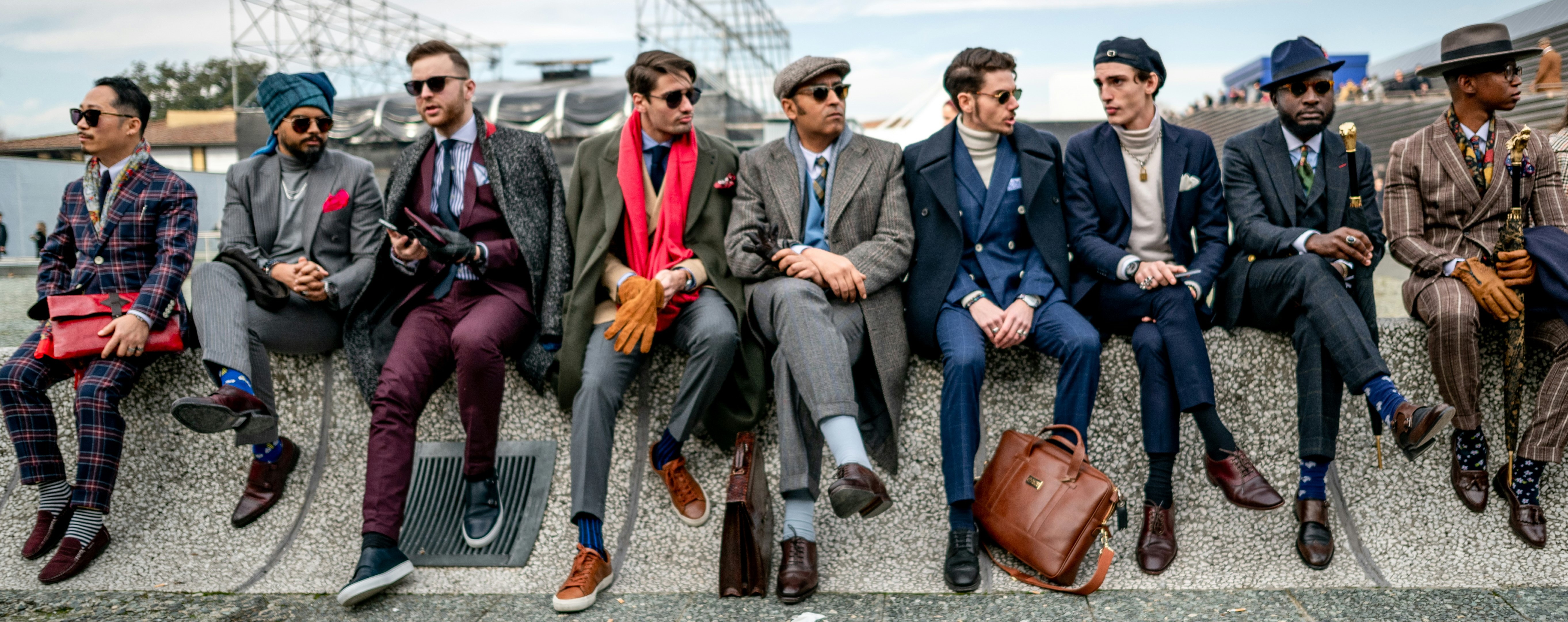 men sitting in a row on a wall